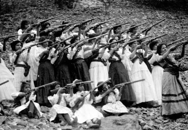 Foto em preto e branco de um grupo de Soldaderas apontando armas sentido nordeste.